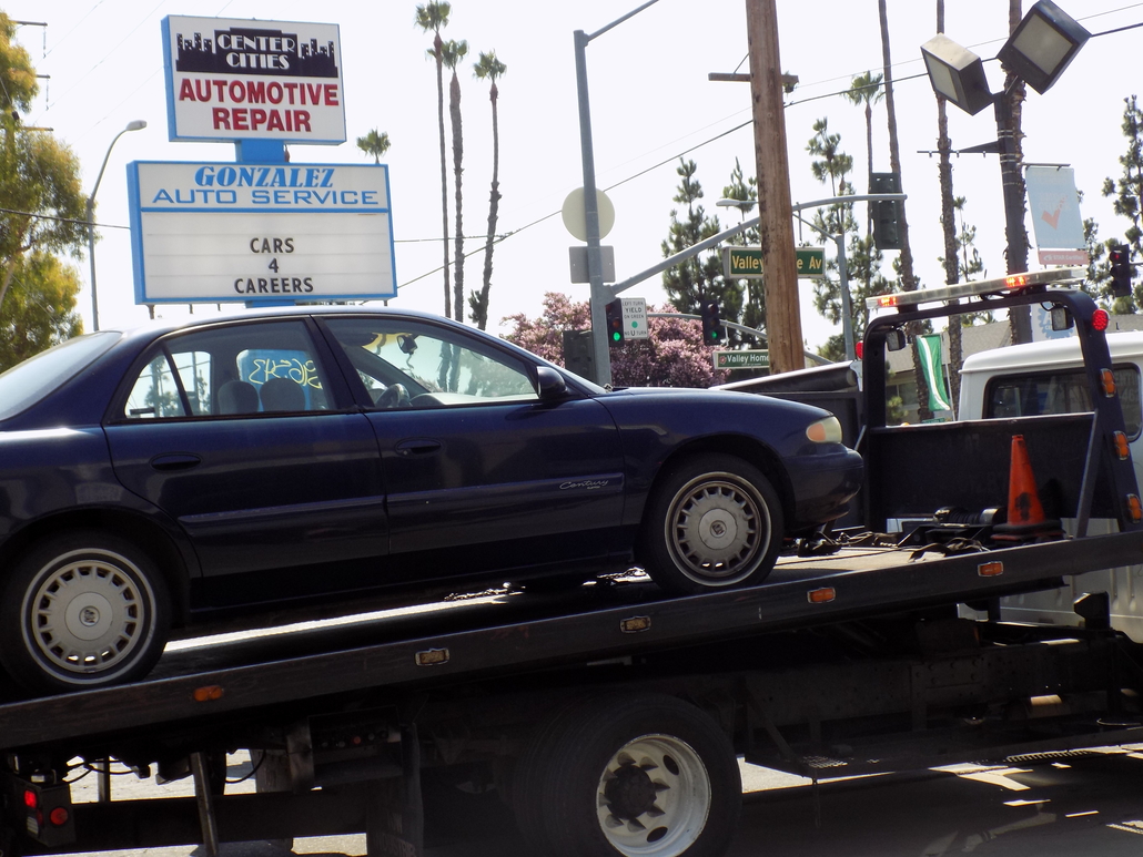 Car on tow truck infront of sign for Center Cities Automotive
